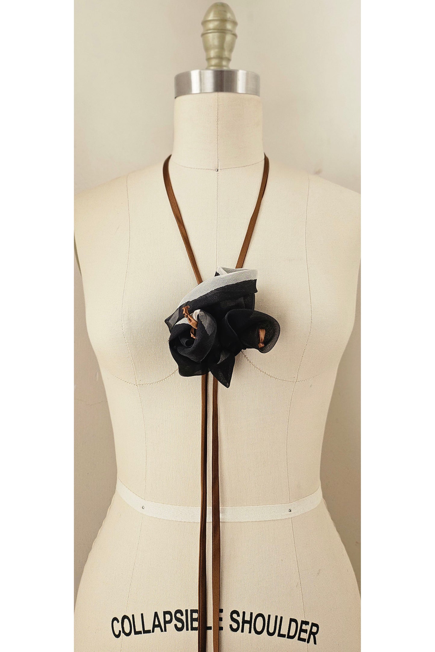 Handmade zero-waste silk bolo tie necklace with adjustable ties and floral accent.